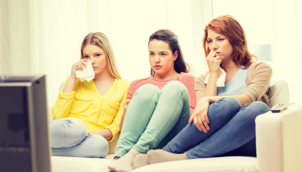 three sad teenage girl watching tv at home